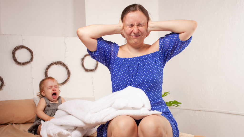 Mutter hält sich die Ohren zu während Baby schreit
